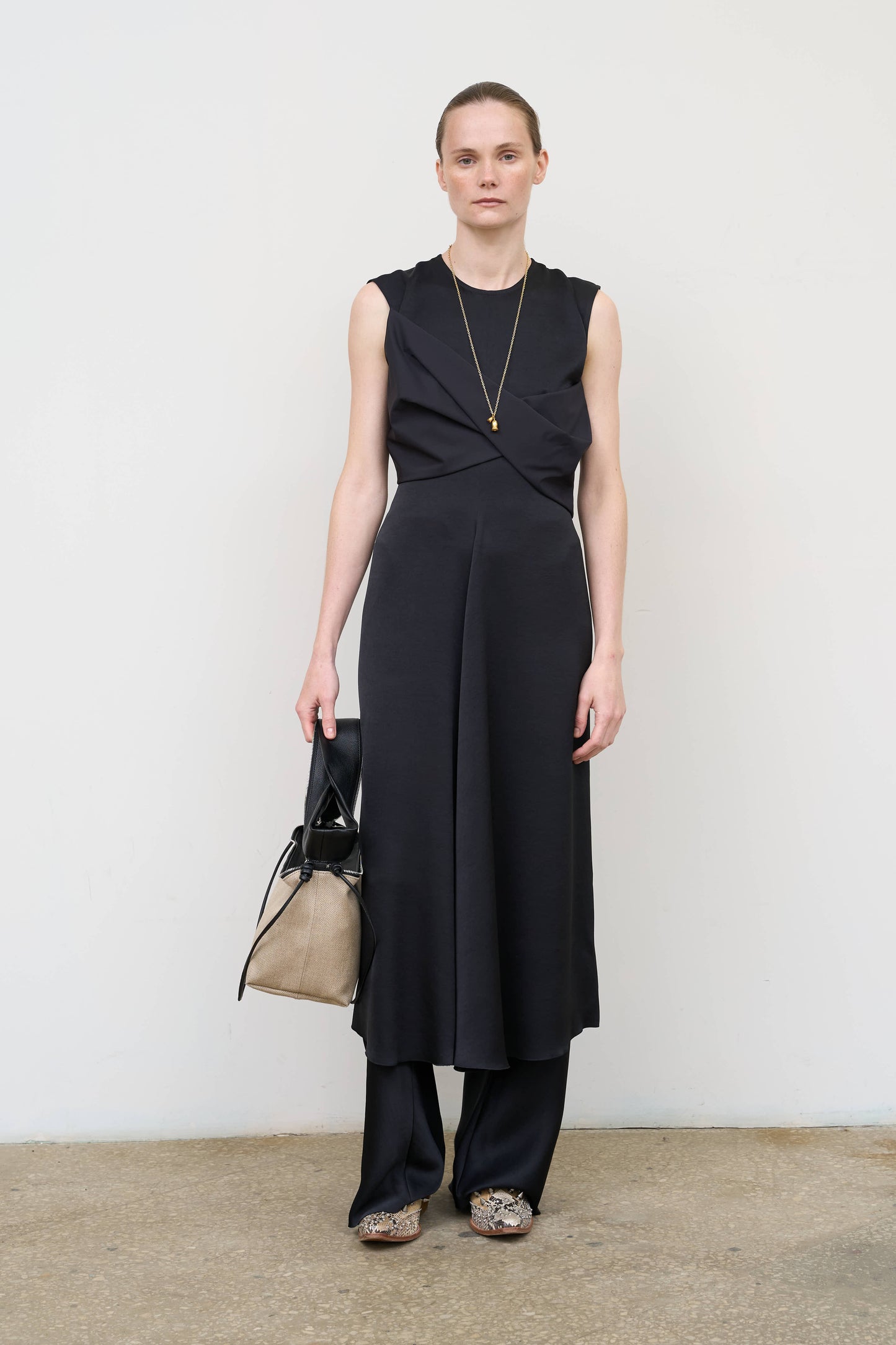 Model is wearing a black waist-twisted satin dress by Litkovska with sculptural twist at the waist and fluid silhouette, designer women’s dress available at House of Woven Stories