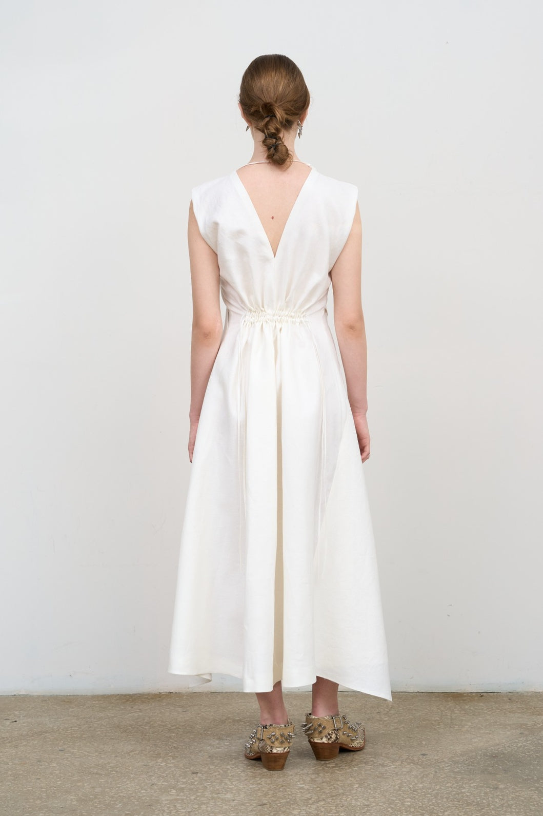 Model is wearing Litkovska white layered midi dress with deep V-neck, sleeveless silhouette, and floral embroidery. A refined, modern, and artisanal piece that belongs to the curated selection of House of Nomad Stories.