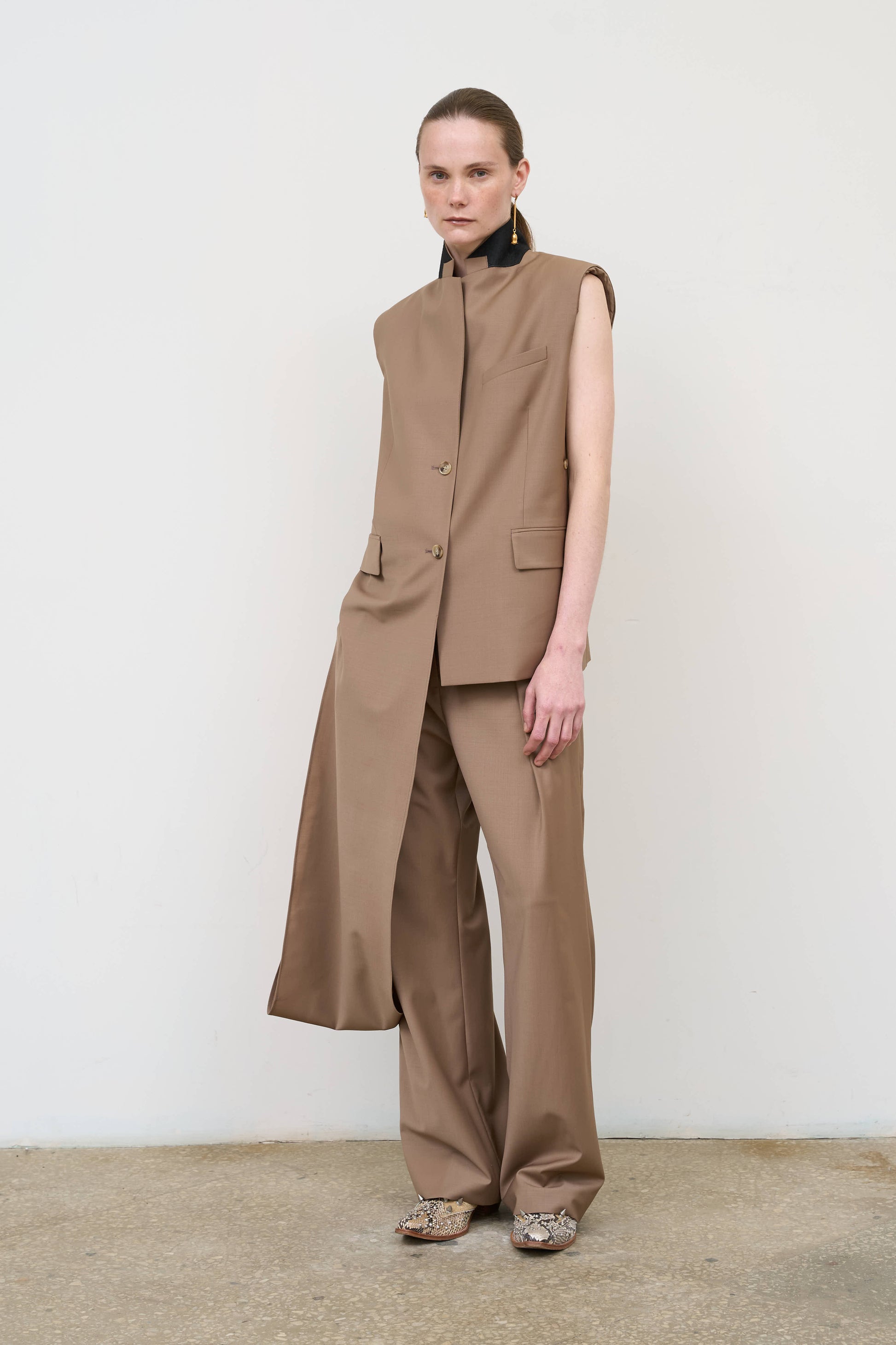 Model is wearing a beige wool-blend deconstructed vest by Litkovska with integrated scarf detail and fluid drape, designer women’s vest available at House of Woven Stories
