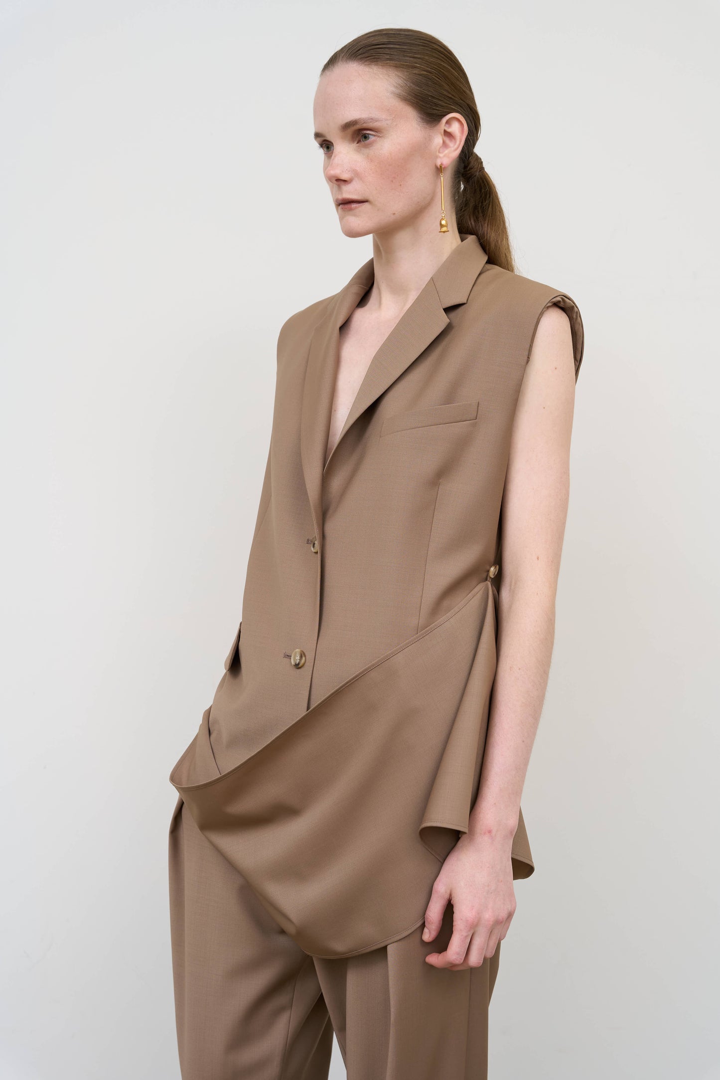 Model is wearing a beige wool-blend deconstructed vest by Litkovska with integrated scarf detail and fluid drape, designer women’s vest available at House of Woven Stories