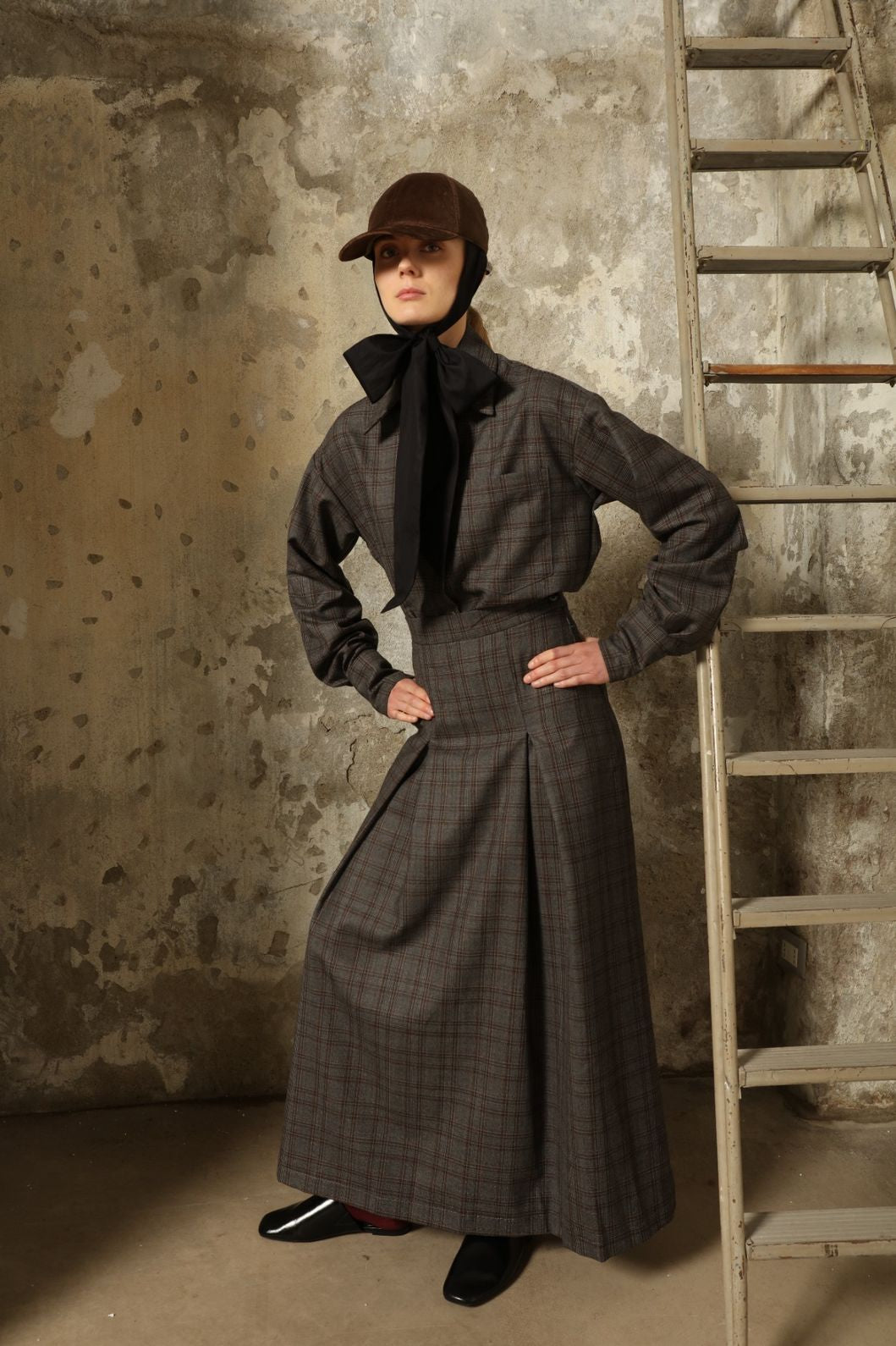 Model is wearing the Londra Brown Checked Skirt by House of Woven Stories, ankle-length with fine pleats and brown checked pattern, combining timeless tailoring with contemporary elegance and quality craftsmanship.