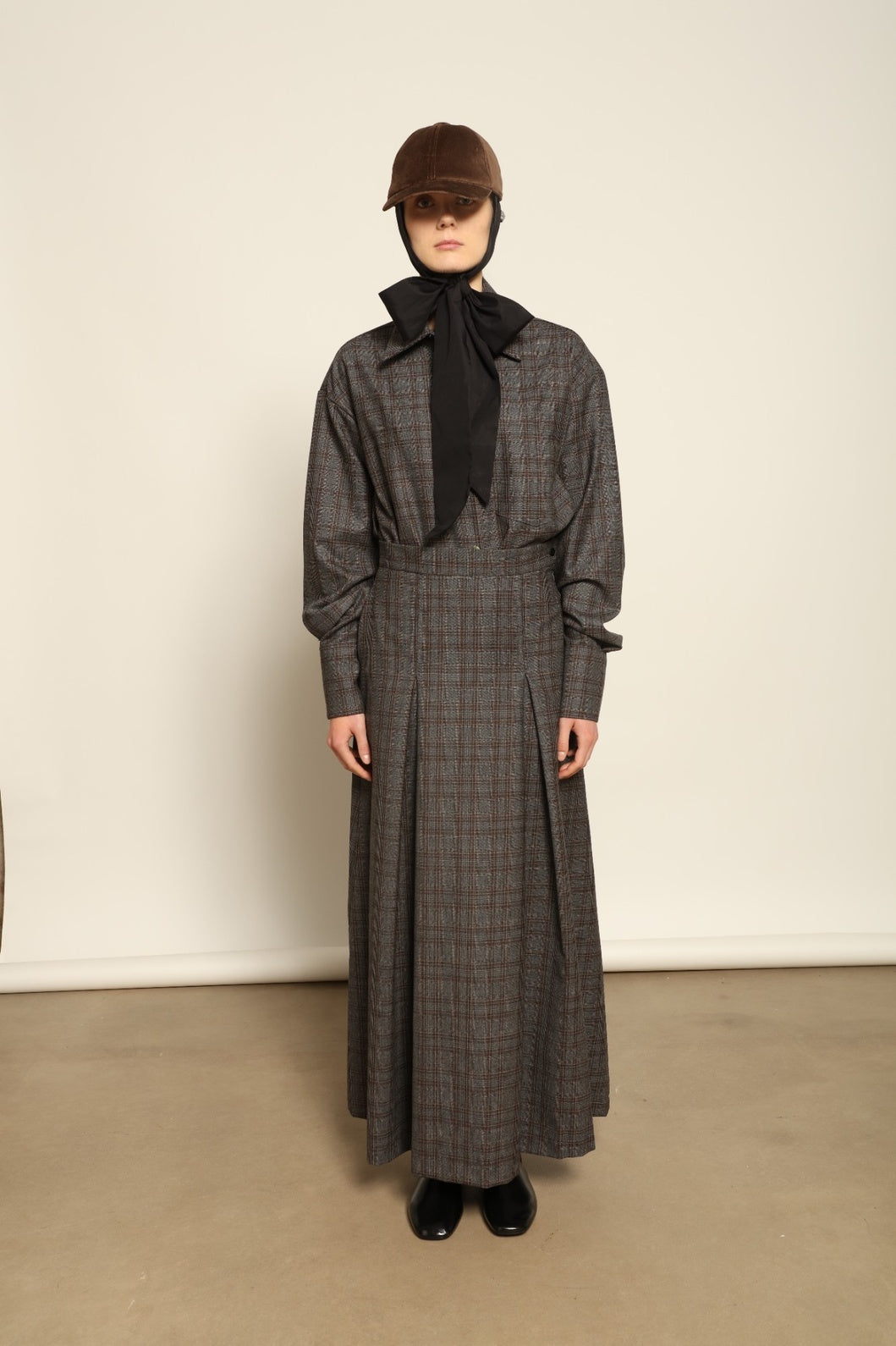 Model is wearing the Londra Brown Checked Skirt by House of Woven Stories, ankle-length with fine pleats and brown checked pattern, combining timeless tailoring with contemporary elegance and quality craftsmanship.