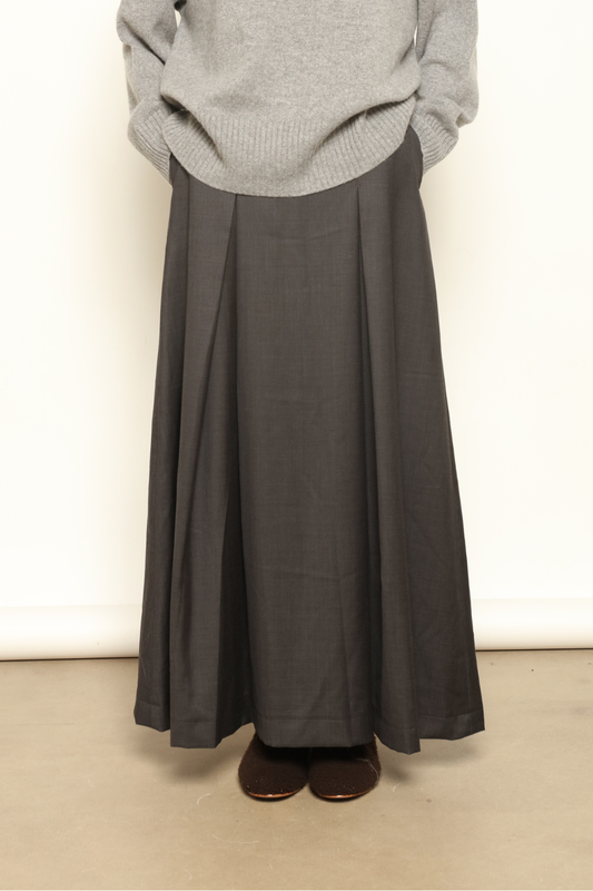 Model is wearing the Londra Grey Merino Wool Skirt by House of Woven Stories – crafted in Italy with subtle pleats, a flattering structured silhouette, and soft grey tones for timeless elegance.