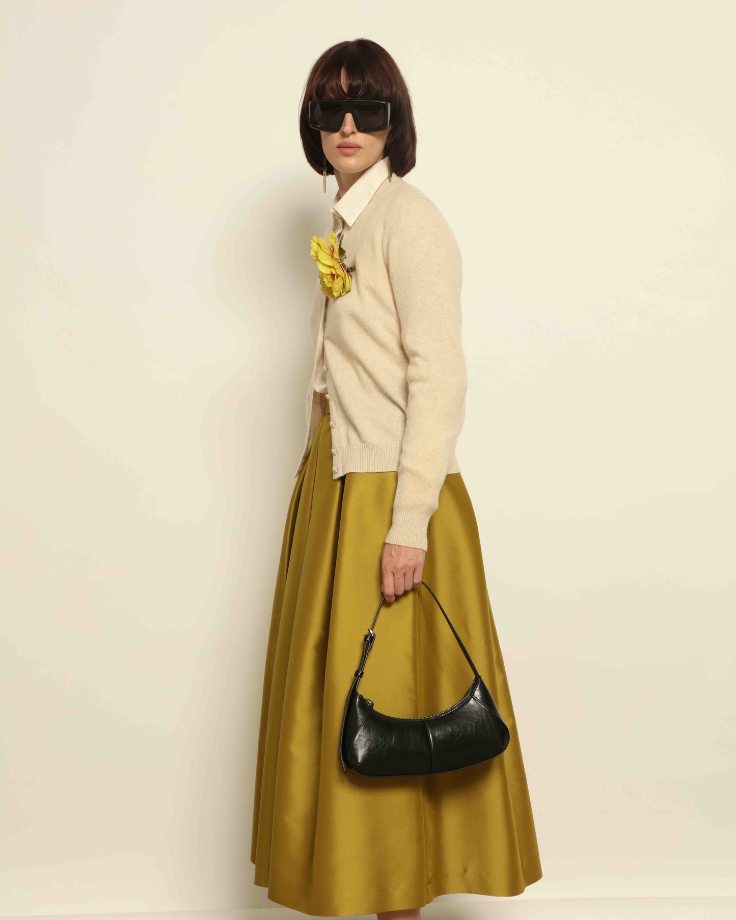 Model is wearing Duchesse Oliva Skirt by Lunatica Milano available at House of Woven Stories. Pleated maxi skirt in a luxurious soft-blend fabric. Elegant, feminine, and handmade in Italy.