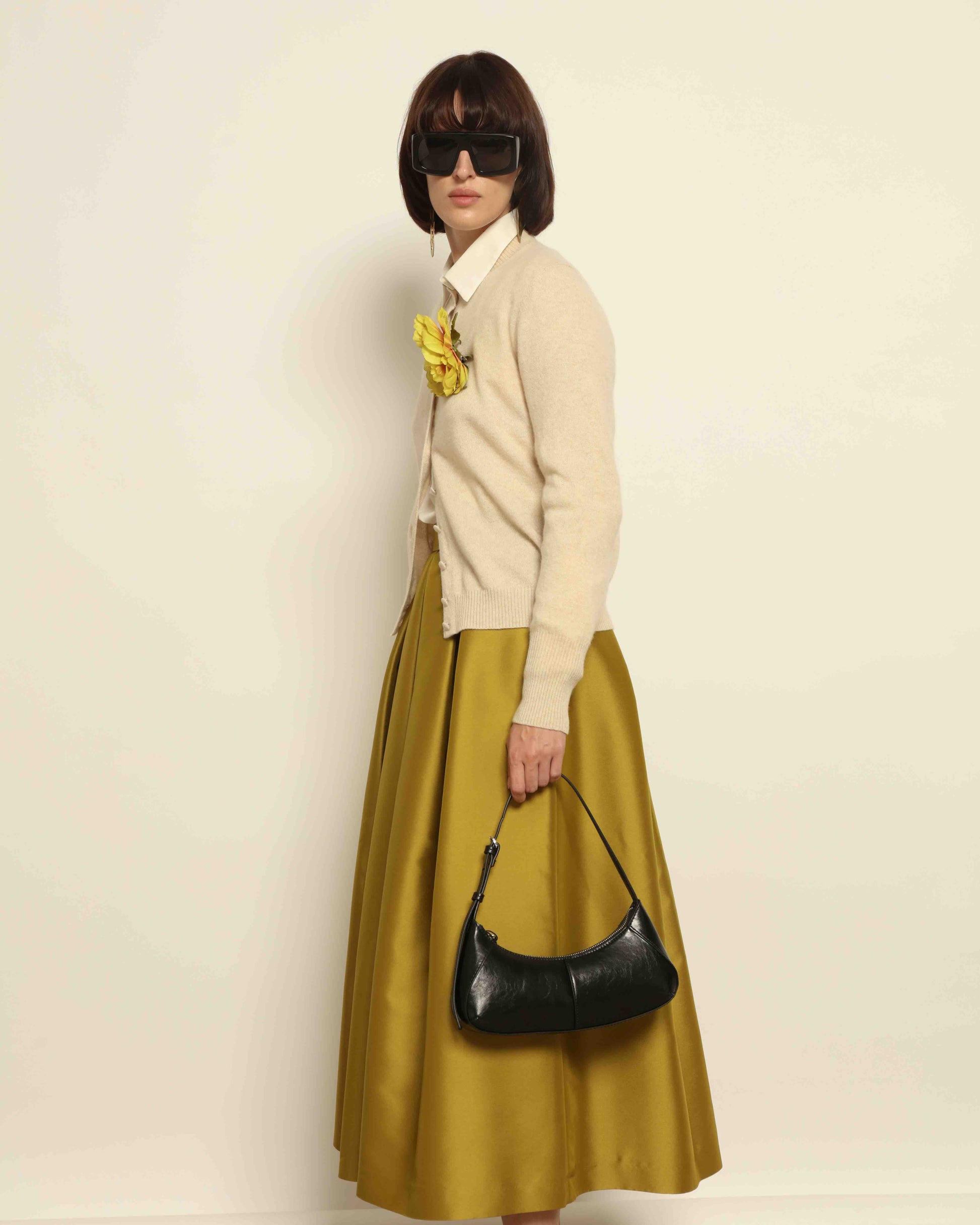 Model is wearing Duchesse Oliva Skirt by Lunatica Milano available at House of Woven Stories. Pleated maxi skirt in a luxurious soft-blend fabric. Elegant, feminine, and handmade in Italy.