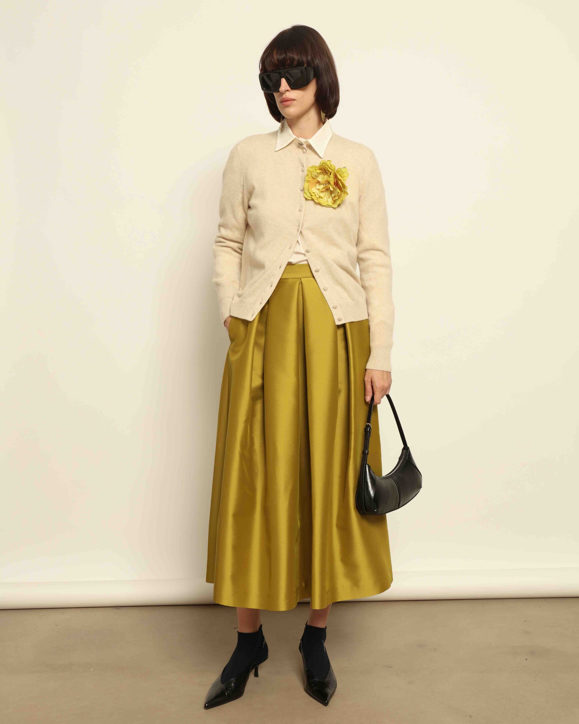 Model is wearing Duchesse Oliva Skirt by Lunatica Milano available at House of Woven Stories. Pleated maxi skirt in a luxurious soft-blend fabric. Elegant, feminine, and handmade in Italy.