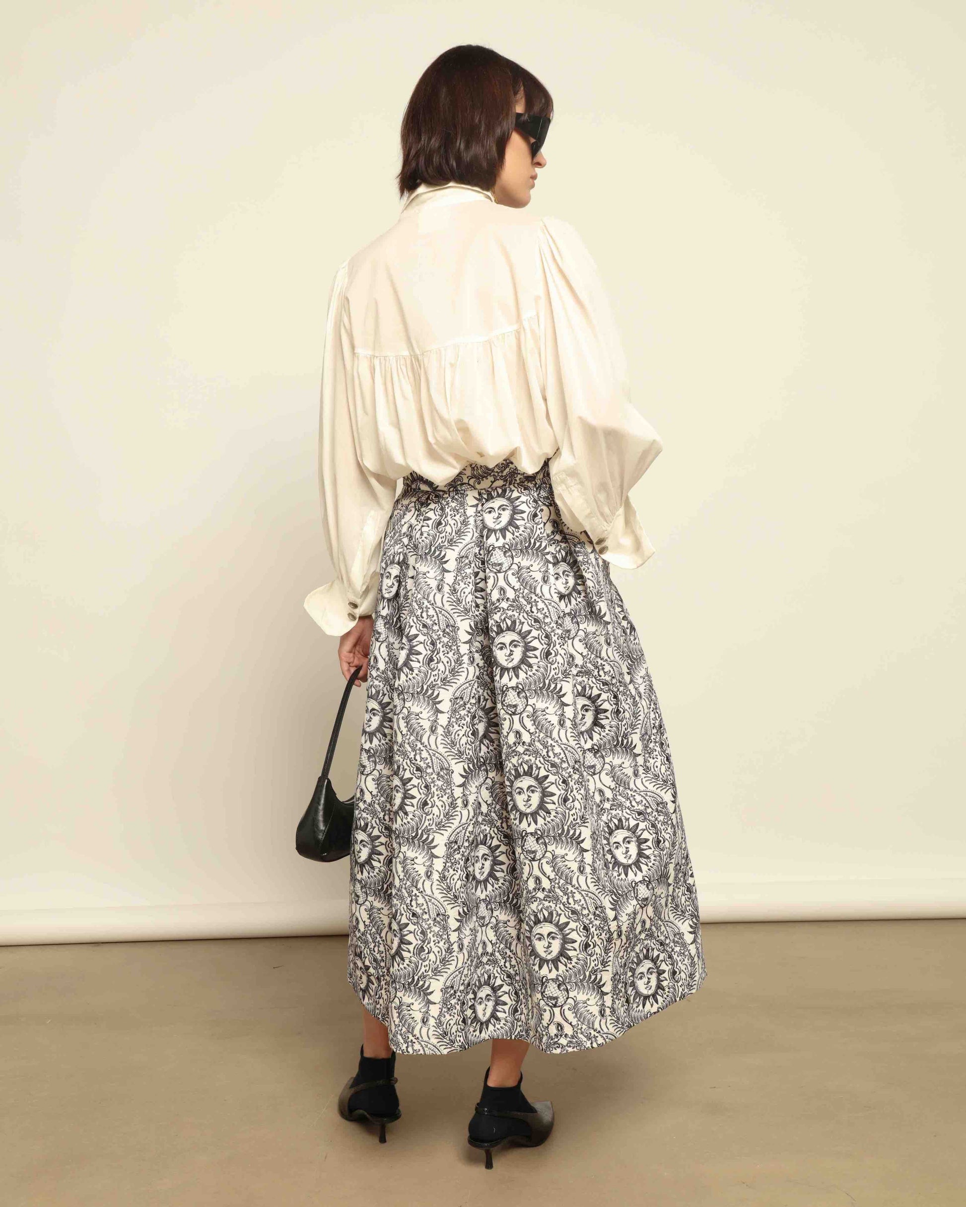 Model is wearing Sun Black and White Skirt by Lunatica Milano. Romantic floral skirt in classic black and white. Elegant, feminine, and handcrafted in Italy. Part of House of Woven Stories selection.