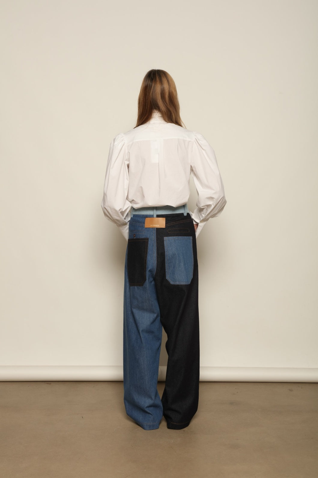 Model is wearing the Carla Denim Patchwork Pant by Maison Jejia, tailored denim trousers crafted from mixed-wash patches with a relaxed structured silhouette and fine stitching, curated in the House of Woven Stories selection