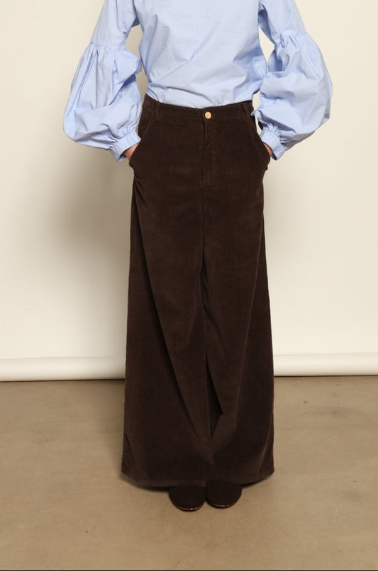 Model is wearing the Maron Foncè Le Pantalon Over Chino by Happy Haus, crafted in soft velour with a wide flowing silhouette, removable belt, back embroidered peacock, and wooden button detail for versatile, relaxed-chic style.