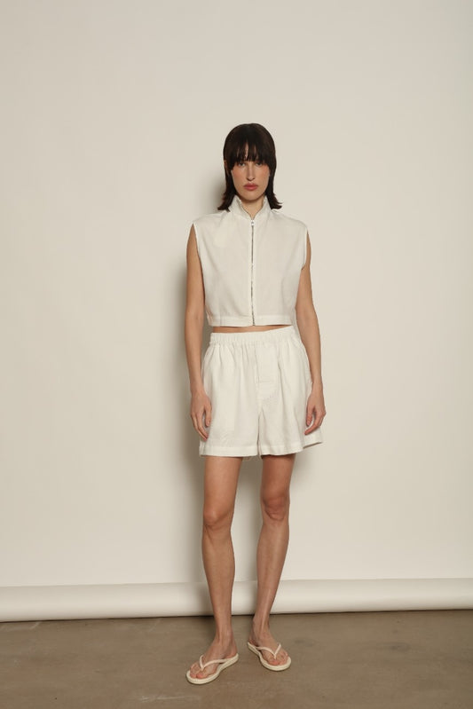 Model is wearing Marrakshi Life cropped turtleneck in white hand-loomed cotton, boxy fit high neck cropped top with minimalist design styled with high-waisted trousers