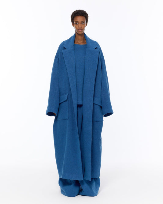 Model is wearing the French Blue Bouclé Blanket Coat by Marrakshi Life, a hand-woven oversized cotton bouclé coat with a deep shawl collar and textured finish, curated in the House of Woven Stories selection.