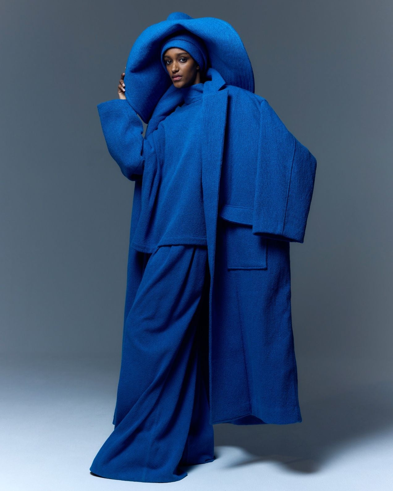 Model is wearing the French Blue Bouclé Blanket Coat by Marrakshi Life, a hand-woven oversized cotton bouclé coat with a deep shawl collar and textured finish, curated in the House of Woven Stories selection.