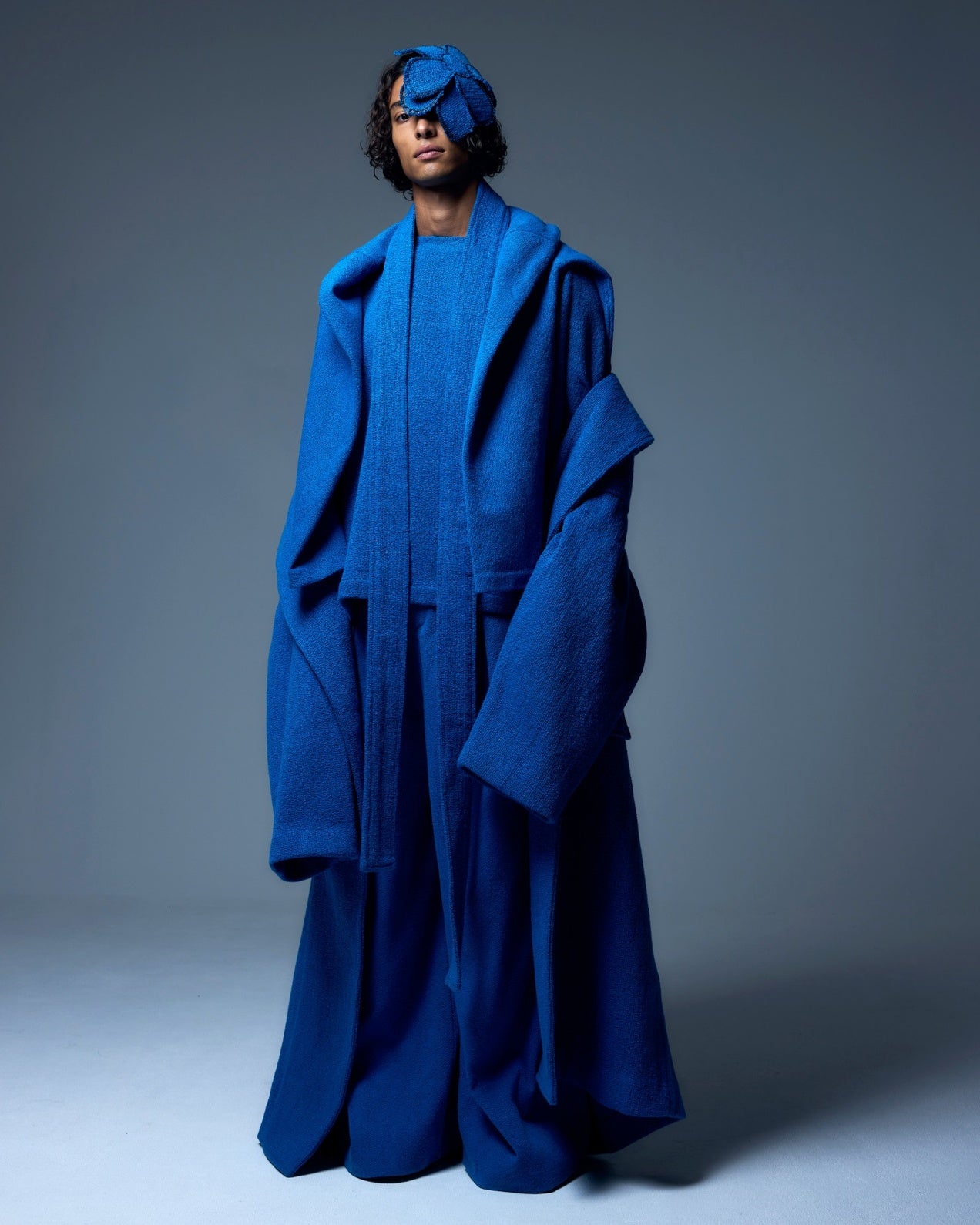 Model is wearing the French Blue Bouclé Blanket Coat by Marrakshi Life, a hand-woven oversized cotton bouclé coat with a deep shawl collar and textured finish, curated in the House of Woven Stories selection.