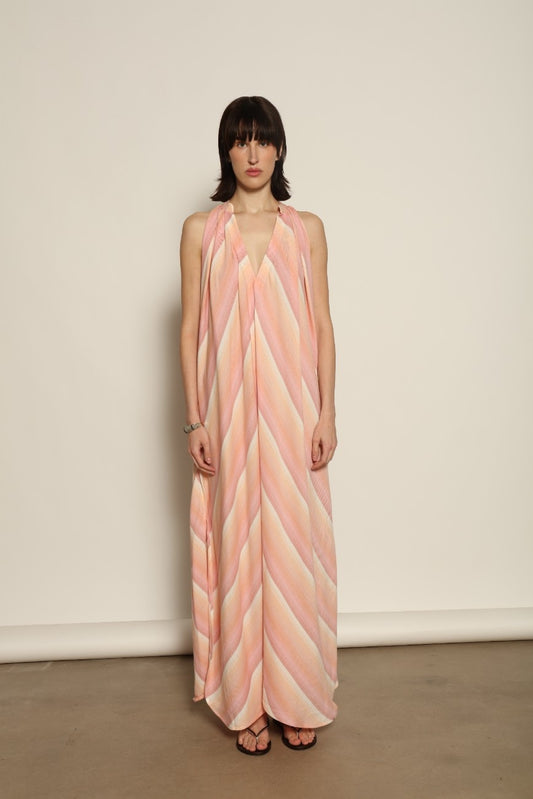 Model is wearing Marrakshi Life halter maxi dress in multicolor striped handwoven cotton, lightweight breathable sleeveless V-neck dress with flowy silhouette and side slits from the curated selection of House of Woven Stories