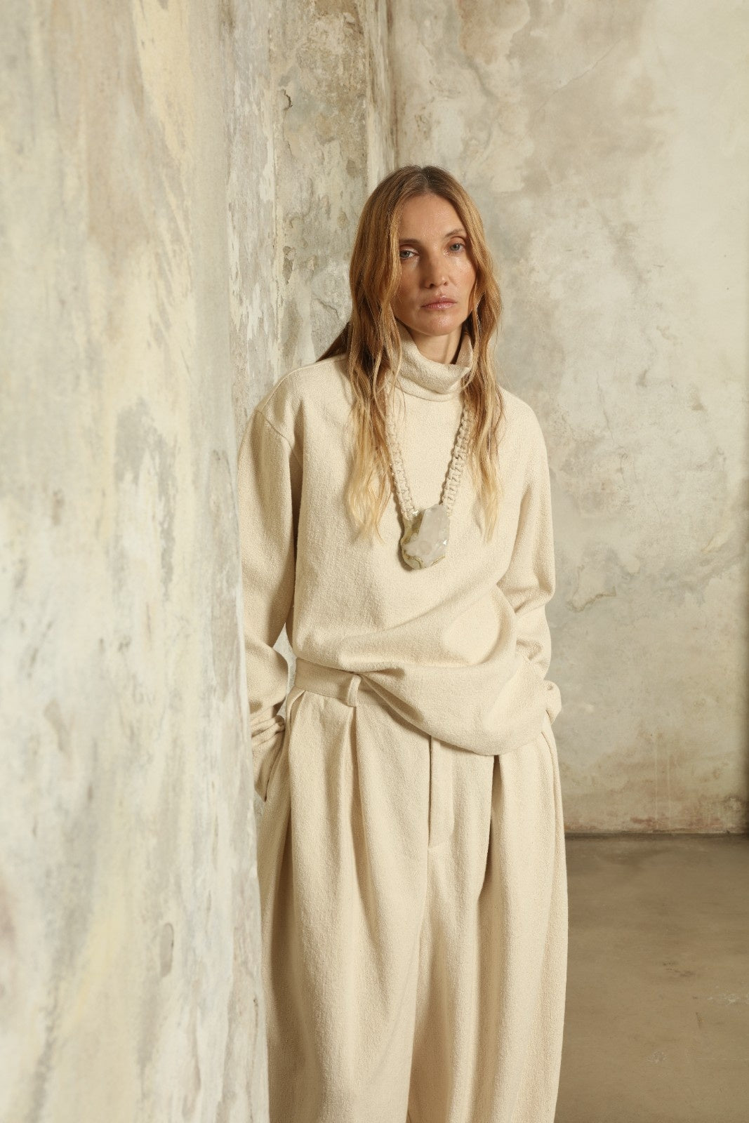 Model is wearing the Mid Rise Ecru Boucle Solid Pant by Marrakshi Life, part of House of Woven Stories collection, handwoven cotton boucle pants with mid-rise fit, front pleats, and wide flowing leg