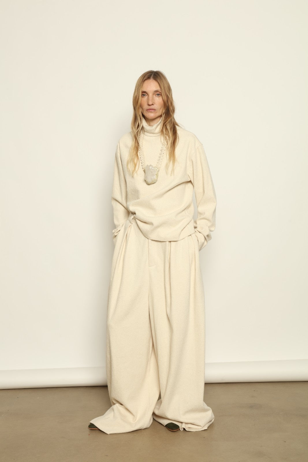 Model is wearing the Mid Rise Ecru Boucle Solid Pant by Marrakshi Life, part of House of Woven Stories collection, handwoven cotton boucle pants with mid-rise fit, front pleats, and wide flowing leg
