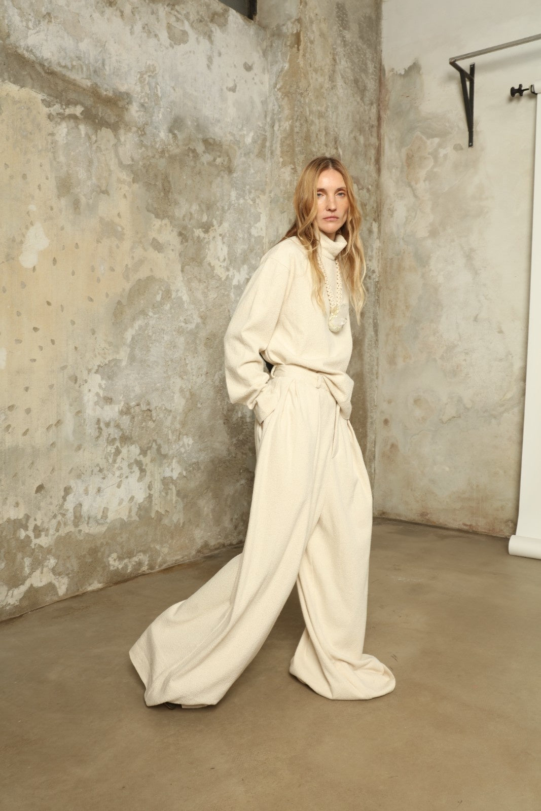 Model is wearing the Mid Rise Ecru Boucle Solid Pant by Marrakshi Life, part of House of Woven Stories collection, handwoven cotton boucle pants with mid-rise fit, front pleats, and wide flowing leg