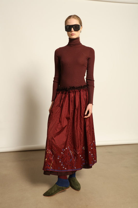 Model is wearing the Miraj 103 Silk Skirt by Injiri, handcrafted in red silk with vibrant rectangular motifs along the hem, blending artistry, movement, and refined elegance.