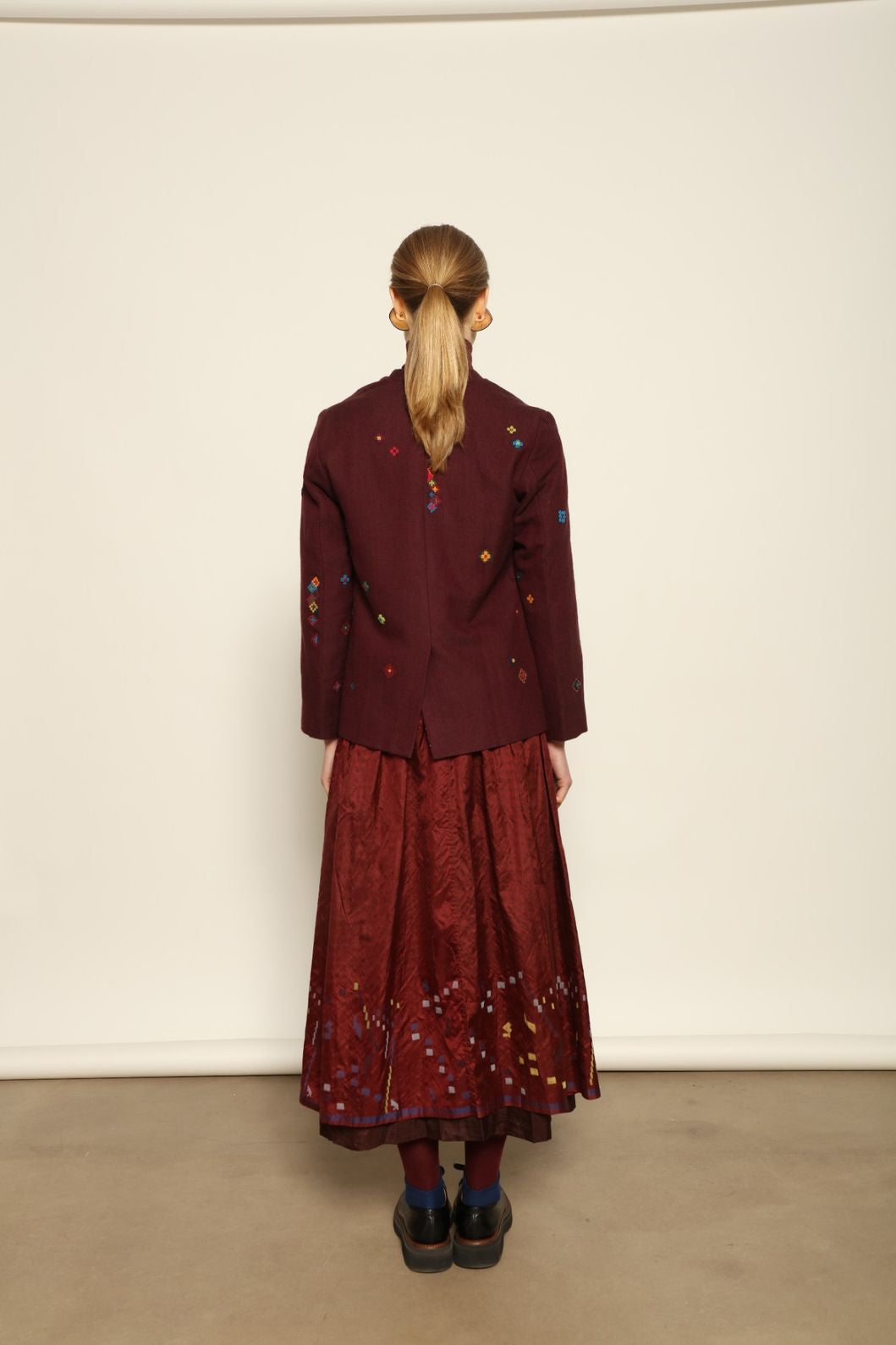 Model is wearing the Miraj 103 Silk Skirt by Injiri, handcrafted in red silk with vibrant rectangular motifs along the hem, blending artistry, movement, and refined elegance.