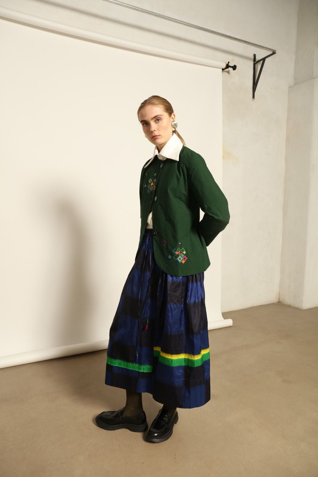 Model is wearing the Miraj 106 Cotton and Silk Skirt by Injiri, handcrafted in India with a blue check base and vibrant green and yellow rectangular motifs, blending heritage craftsmanship with bold contemporary design.