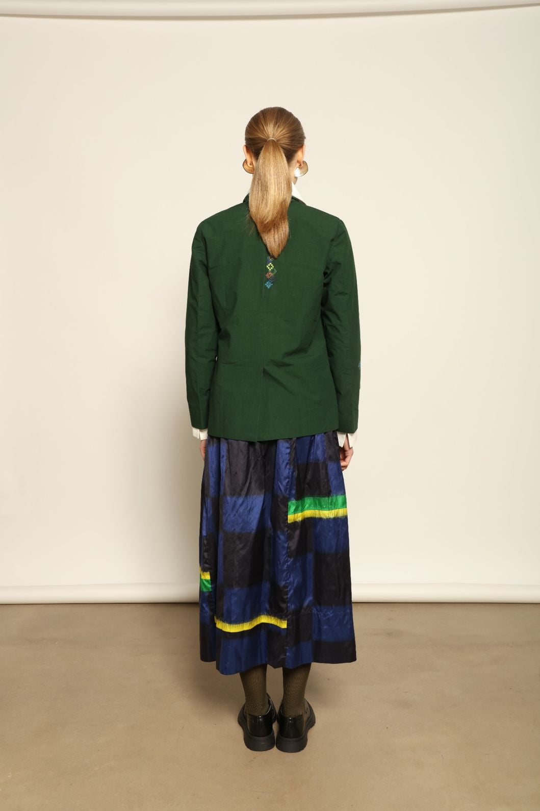 Model is wearing the Miraj 106 Cotton and Silk Skirt by Injiri, handcrafted in India with a blue check base and vibrant green and yellow rectangular motifs, blending heritage craftsmanship with bold contemporary design.