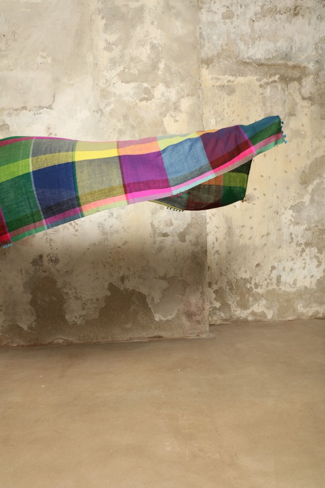 Model is wearing the Miraj 135 Cashmere Scarf by Injiri, handwoven from Himalayan cashmere with a multicolored Madras check and playful rounded borders, blending softness, warmth, and artisanal elegance.