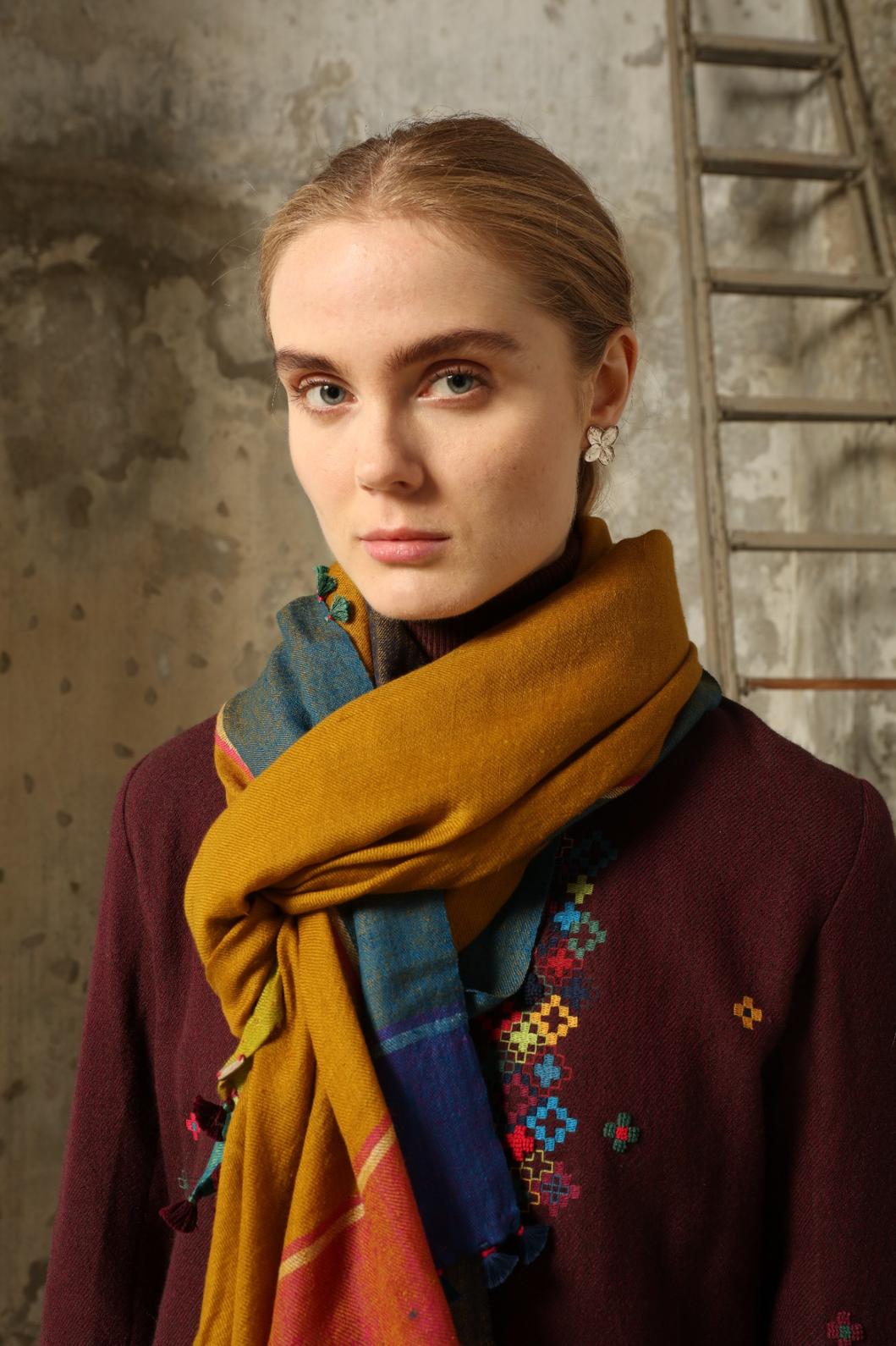 Model is wearing the Miraj 140 Cashmere Scarf by Injiri, handwoven from Kashmir cashmere with a vibrant ochre base and multicolor block borders, blending warmth, softness, and artisanal craftsmanship.