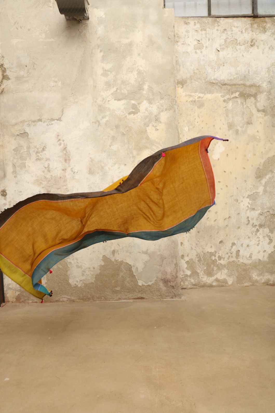 Model is wearing the Miraj 140 Cashmere Scarf by Injiri, handwoven from Kashmir cashmere with a vibrant ochre base and multicolor block borders, blending warmth, softness, and artisanal craftsmanship.