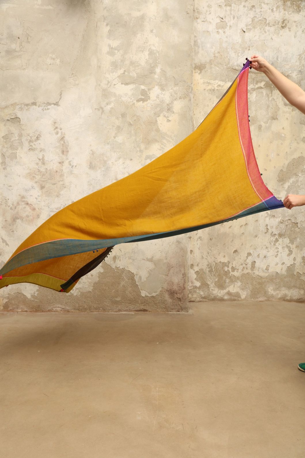 Model is wearing the Miraj 140 Cashmere Scarf by Injiri, handwoven from Kashmir cashmere with a vibrant ochre base and multicolor block borders, blending warmth, softness, and artisanal craftsmanship.