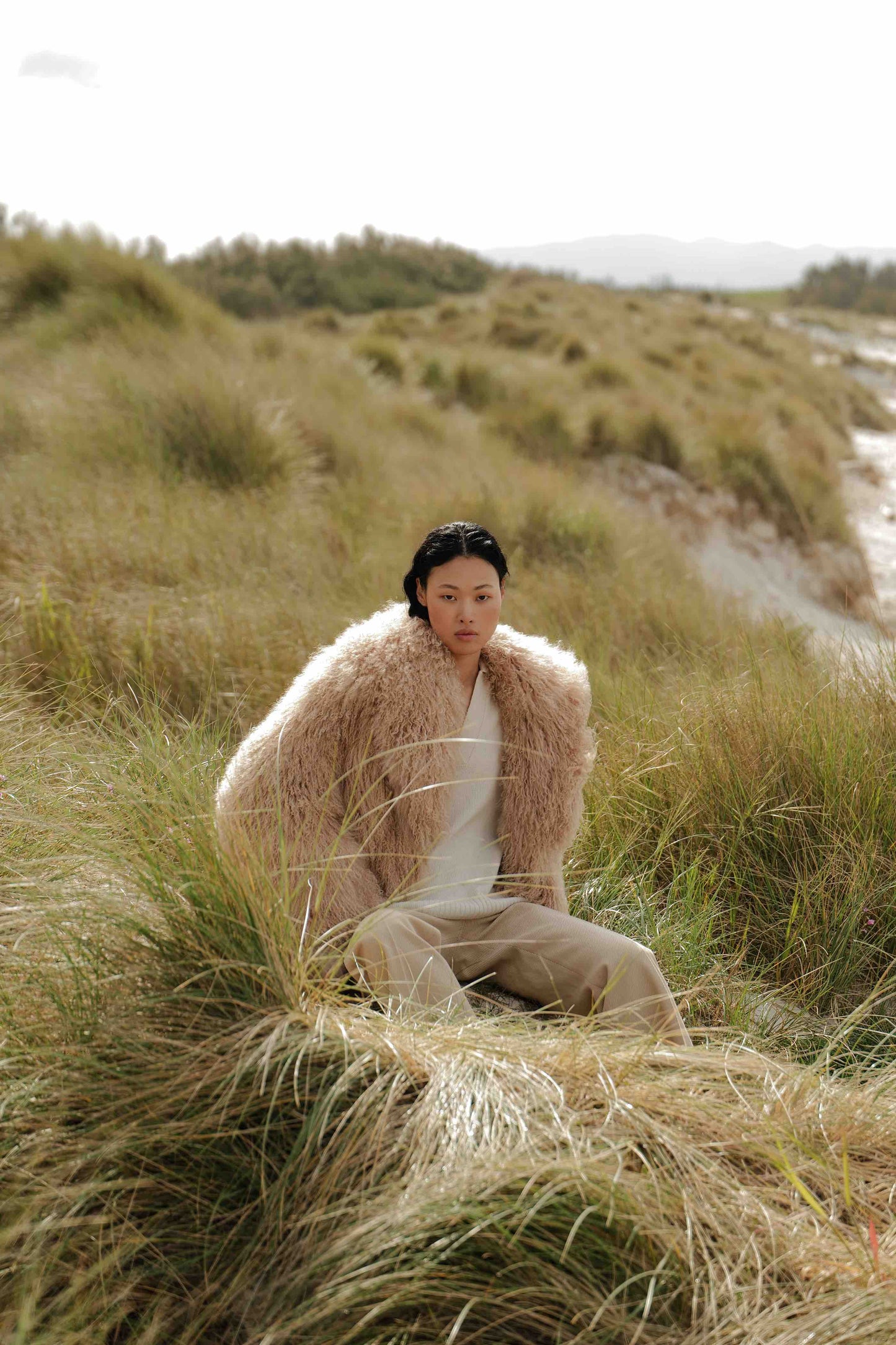 Model is wearing the Mongolia Camel Shearling Jacket by Blancha, part of the House of Woven Stories selection, crafted from 100% Tibet lamb with silk lining, featuring soft, voluminous texture and warm camel tone.