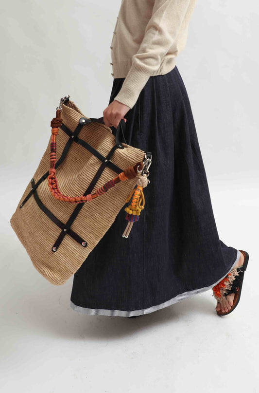 Candide bag made from natural raffia, handcrafted in Belgium. Lightweight and spacious with a casual, refined look. Shown with the colorful Alice Strap by MY BOB (sold separately) for added style and function.