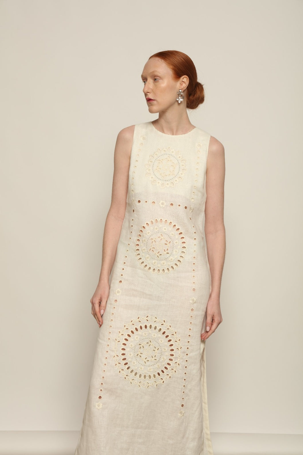 Model is wearing the My Sleeping Gypsy Champenois Dress, an ivory linen dress with hand-cut lace, delicate embroidery, and 24-carat bead accents, from the House of Nomad Stories selection.
