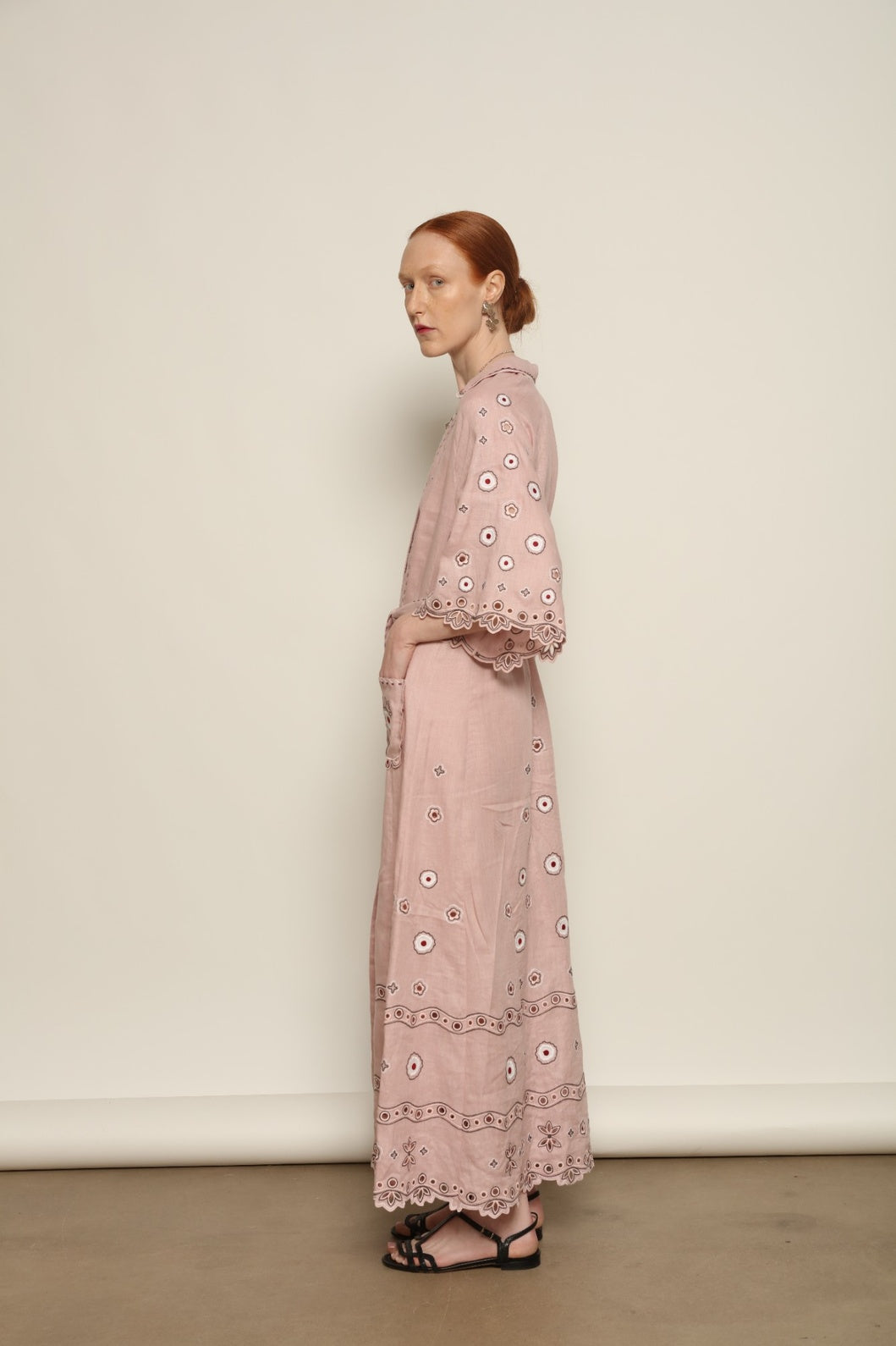 Model is wearing the My Sleeping Gypsy Glass House Long Dress in powder pink linen with Zbiranka pleating, Richelieu embroidery, and 24-carat bead accents, from the House of Nomad Stories selection.
