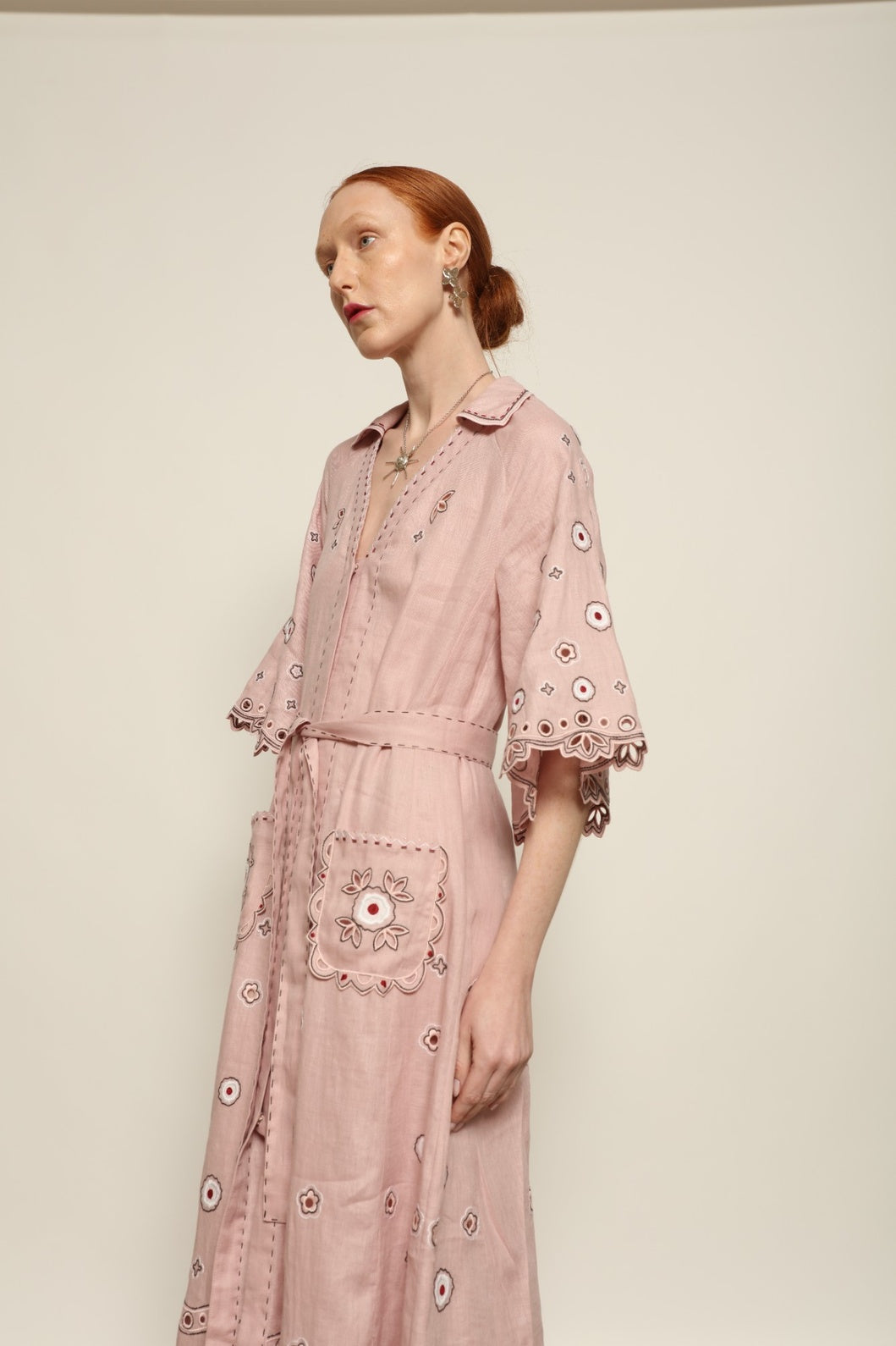 Model is wearing the My Sleeping Gypsy Glass House Long Dress in powder pink linen with Zbiranka pleating, Richelieu embroidery, and 24-carat bead accents, from the House of Nomad Stories selection.
