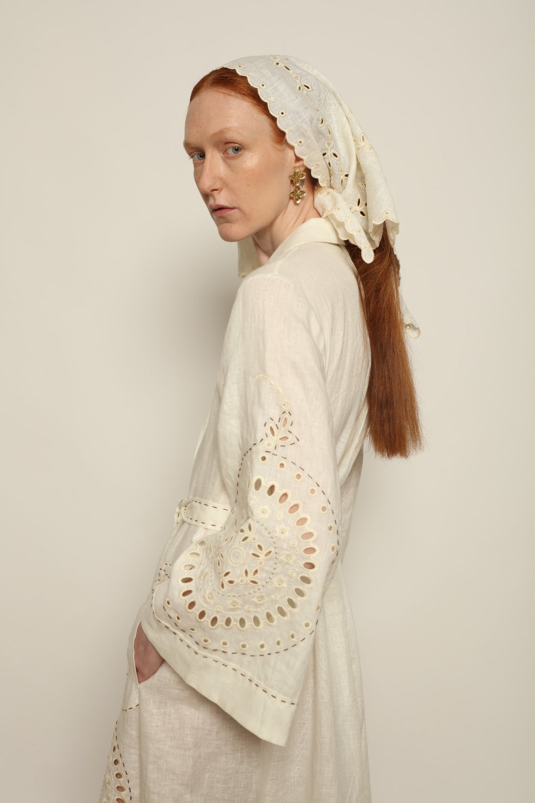 Model is wearing the My Sleeping Gypsy Sarah Long Dress in Ivory, handcrafted from linen with delicate lace, embroidery, and 24-carat bead accents, from the House of Nomad Stories selection.