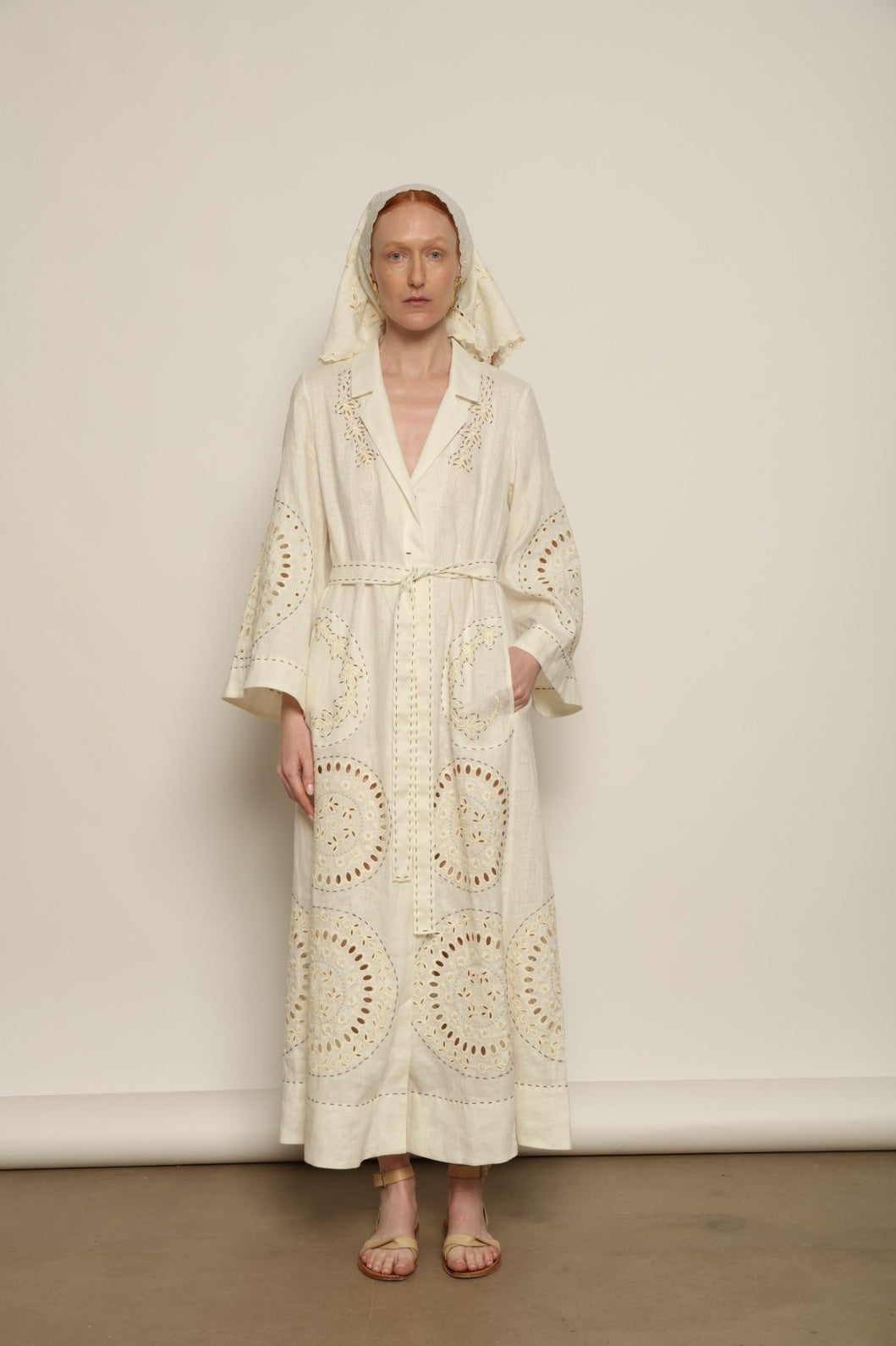 Model is wearing the My Sleeping Gypsy Sarah Long Dress in Ivory, handcrafted from linen with delicate lace, embroidery, and 24-carat bead accents, from the House of Nomad Stories selection.