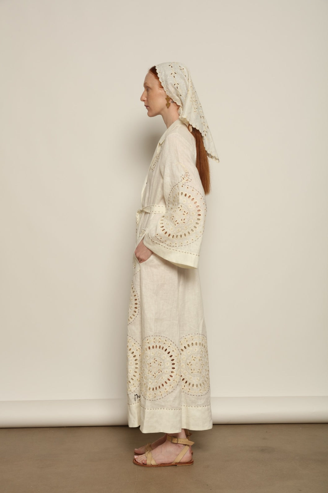 Model is wearing the My Sleeping Gypsy Sarah Long Dress in Ivory, handcrafted from linen with delicate lace, embroidery, and 24-carat bead accents, from the House of Nomad Stories selection.