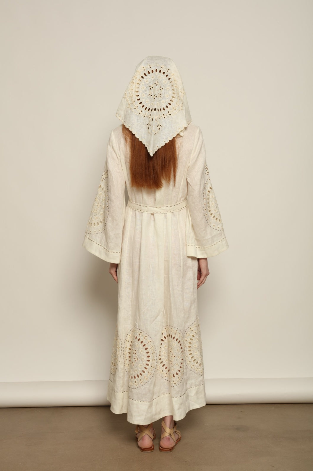 Model is wearing the My Sleeping Gypsy Sarah Long Dress in Ivory, handcrafted from linen with delicate lace, embroidery, and 24-carat bead accents, from the House of Nomad Stories selection.