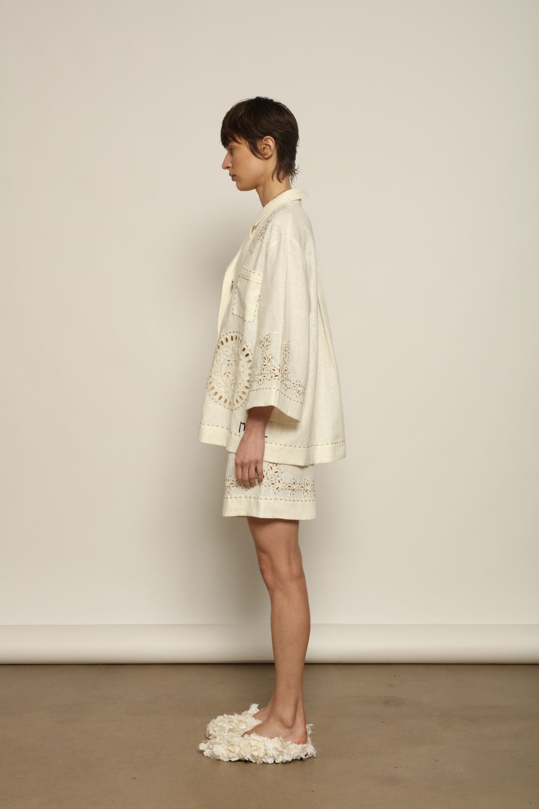 Model is wearing the My Sleeping Gypsy Sarah Suit, a handcrafted ivory linen set with high-waisted shorts, relaxed jacket, intricate embroidery, and 24-carat bead accents, from the House of Nomad Stories selection.