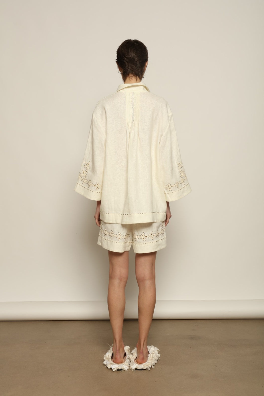 Model is wearing the My Sleeping Gypsy Sarah Suit, a handcrafted ivory linen set with high-waisted shorts, relaxed jacket, intricate embroidery, and 24-carat bead accents, from the House of Nomad Stories selection.