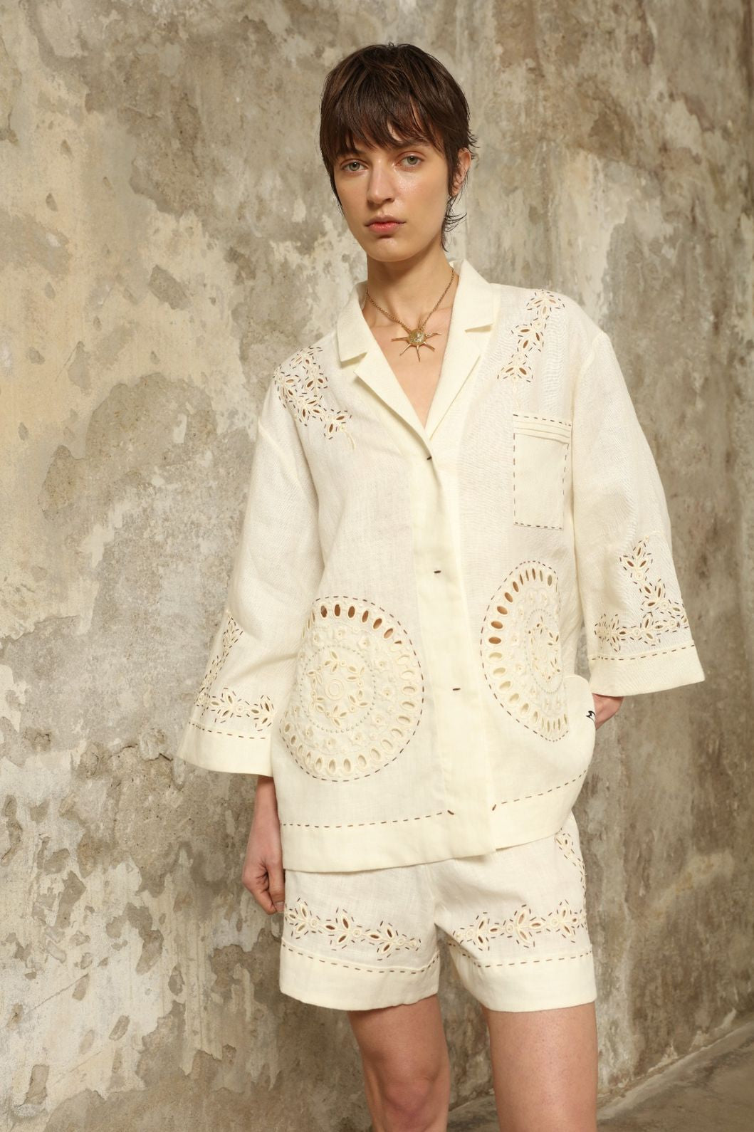 Model is wearing the My Sleeping Gypsy Sarah Suit, a handcrafted ivory linen set with high-waisted shorts, relaxed jacket, intricate embroidery, and 24-carat bead accents, from the House of Nomad Stories selection.