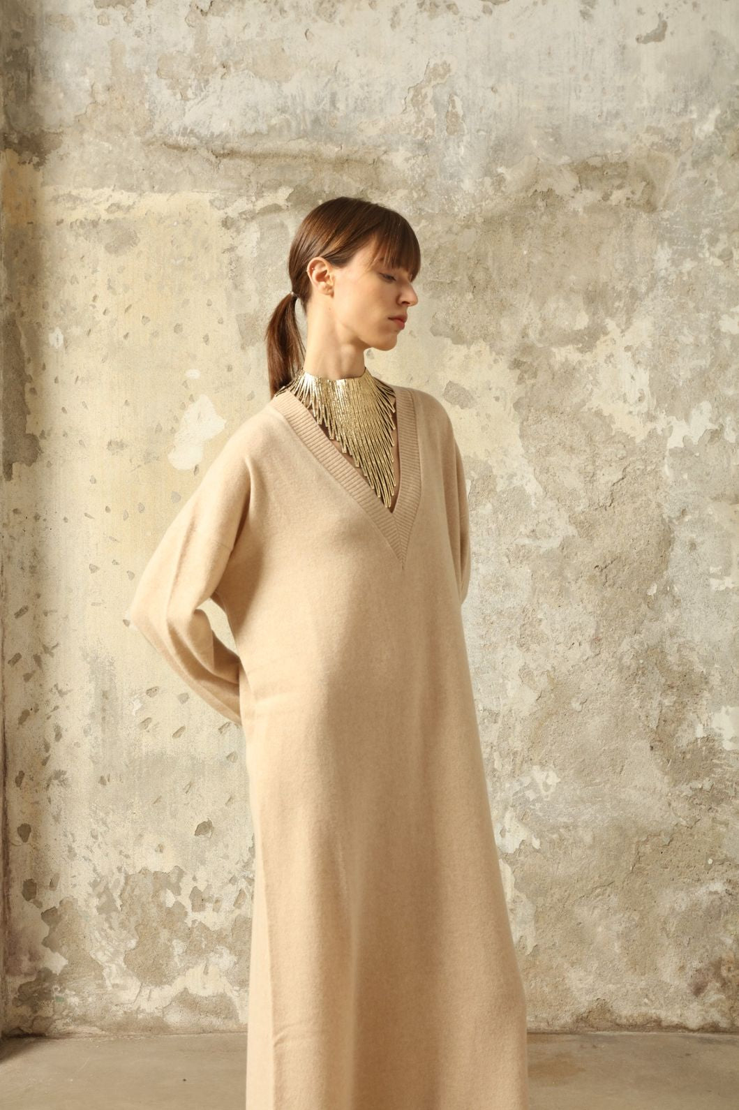 Model is wearing the Natural Katharina V-Neck Cashmere Maxi Dress by House of Woven Stories, crafted from 100% pure Inner Mongolia cashmere in its uncoloured natural shade, featuring a long flowing silhouette, soft breathable knit, elegant V-neckline, and timeless sustainable luxury design