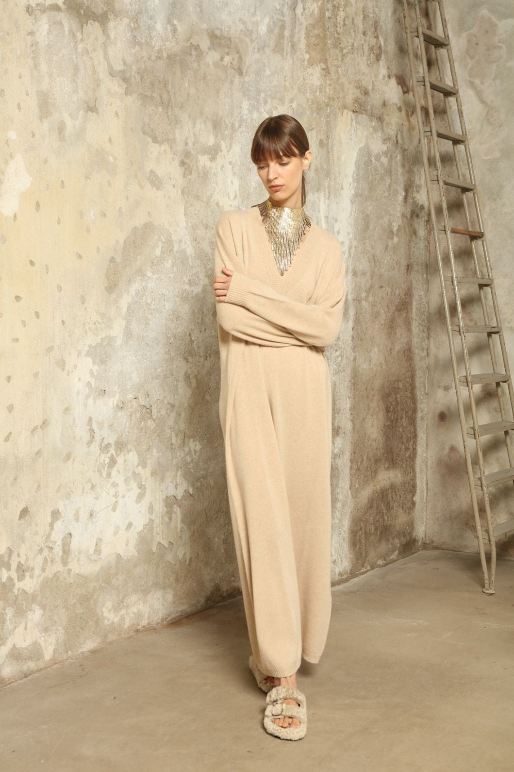 Model is wearing the Natural Katharina V-Neck Cashmere Maxi Dress by House of Woven Stories, crafted from 100% pure Inner Mongolia cashmere in its uncoloured natural shade, featuring a long flowing silhouette, soft breathable knit, elegant V-neckline, and timeless sustainable luxury design