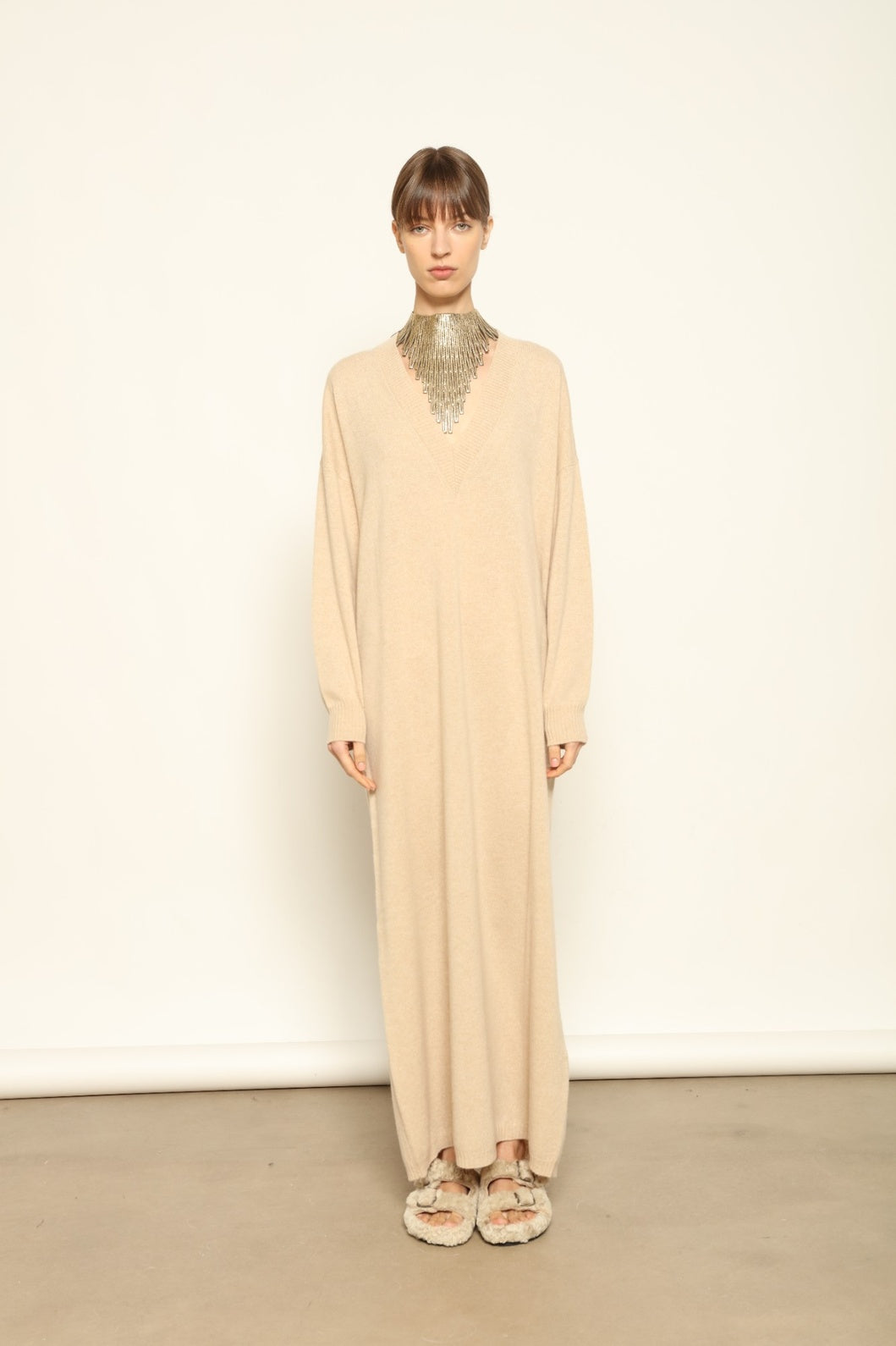 Model is wearing the Natural Katharina V-Neck Cashmere Maxi Dress by House of Woven Stories, crafted from 100% pure Inner Mongolia cashmere in its uncoloured natural shade, featuring a long flowing silhouette, soft breathable knit, elegant V-neckline, and timeless sustainable luxury design