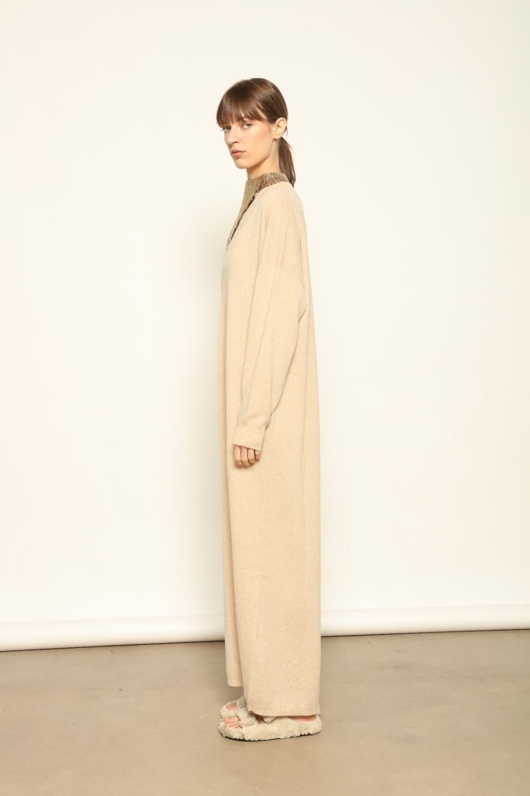 Model is wearing the Natural Katharina V-Neck Cashmere Maxi Dress by House of Woven Stories, crafted from 100% pure Inner Mongolia cashmere in its uncoloured natural shade, featuring a long flowing silhouette, soft breathable knit, elegant V-neckline, and timeless sustainable luxury design