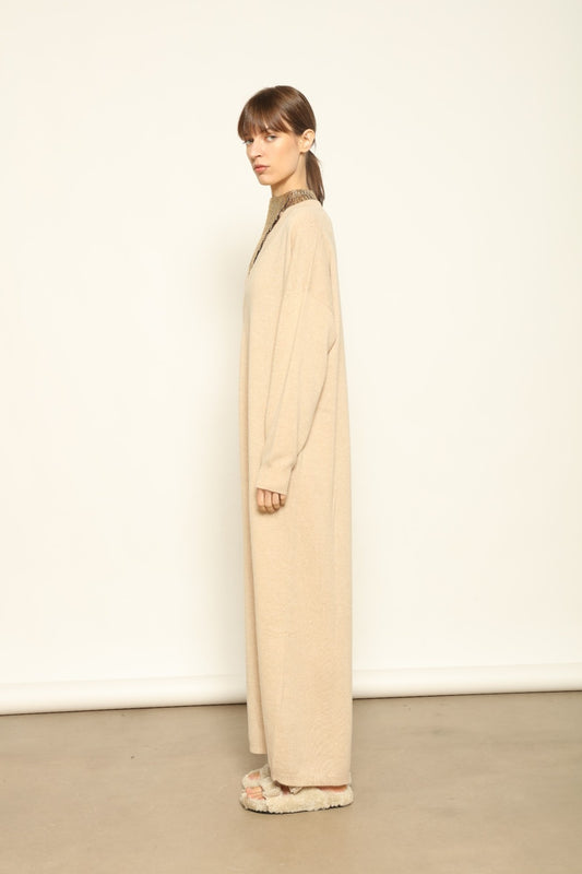 Model is wearing the Natural Katharina V-Neck Cashmere Maxi Dress by House of Woven Stories, crafted from 100% pure Inner Mongolia cashmere in its uncoloured natural shade, featuring a long flowing silhouette, soft breathable knit, elegant V-neckline, and timeless sustainable luxury design