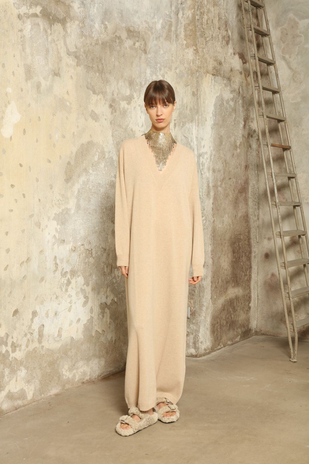 Model is wearing the Natural Katharina V-Neck Cashmere Maxi Dress by House of Woven Stories, crafted from 100% pure Inner Mongolia cashmere in its uncoloured natural shade, featuring a long flowing silhouette, soft breathable knit, elegant V-neckline, and timeless sustainable luxury design
