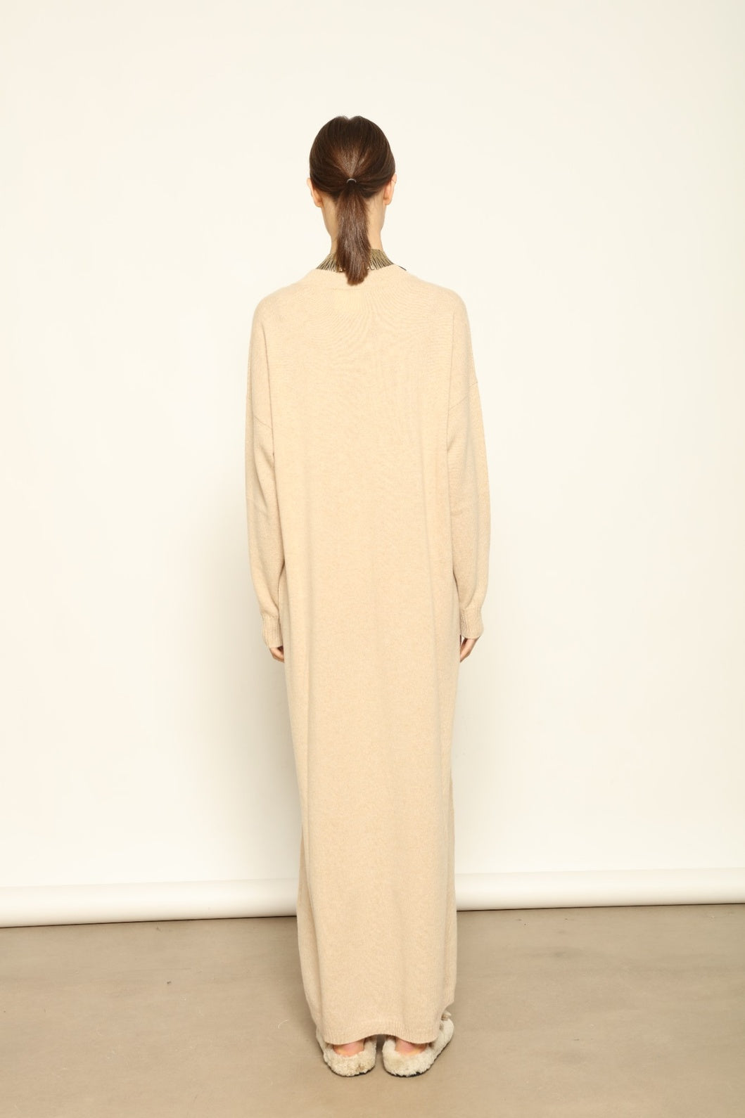 Model is wearing the Natural Katharina V-Neck Cashmere Maxi Dress by House of Woven Stories, crafted from 100% pure Inner Mongolia cashmere in its uncoloured natural shade, featuring a long flowing silhouette, soft breathable knit, elegant V-neckline, and timeless sustainable luxury design