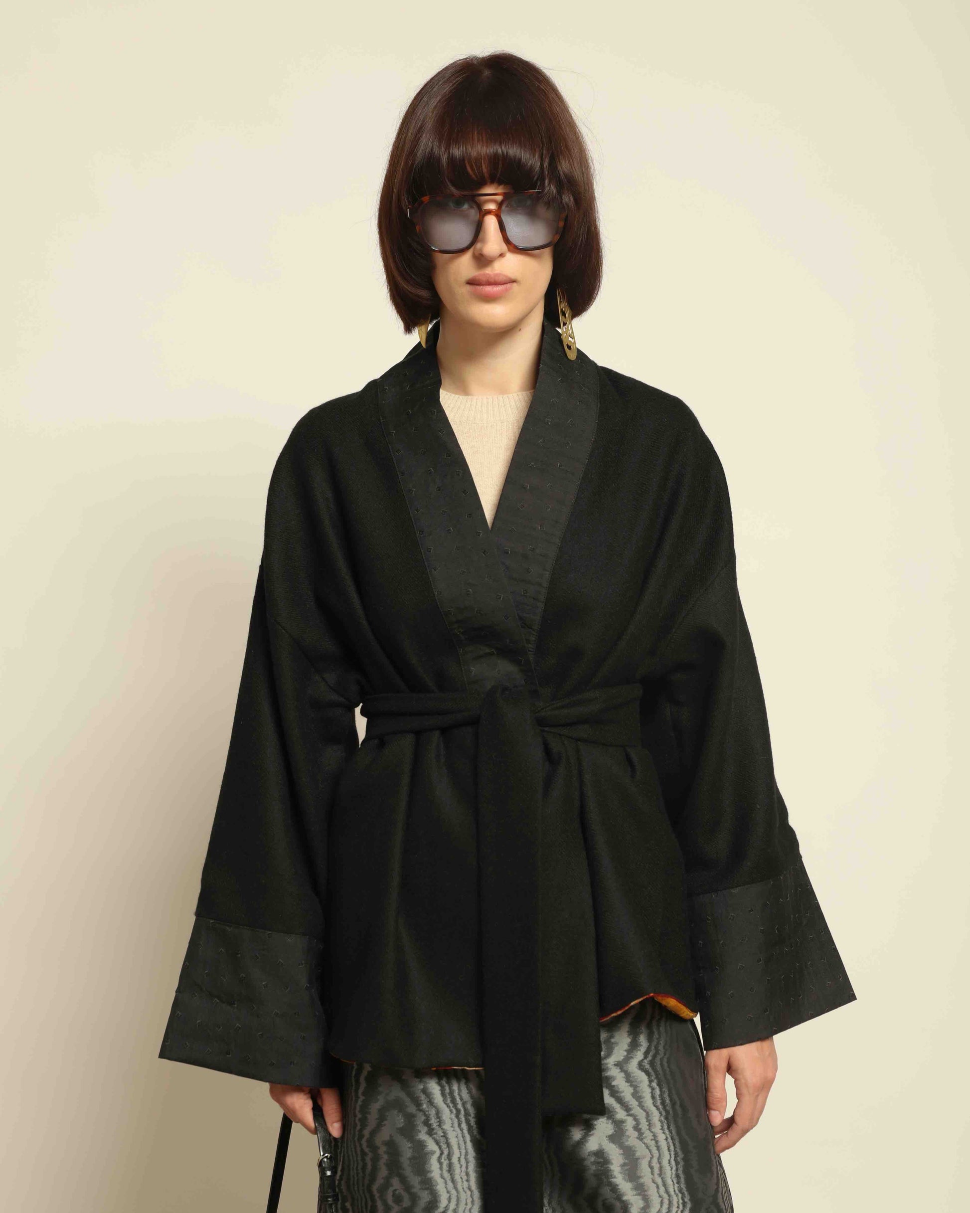 The model is wearing the Obidi Midnight Kantha Jacket in pure black, made of wool with a silk collar and Kantha silk lining, a timeless and versatile piece.