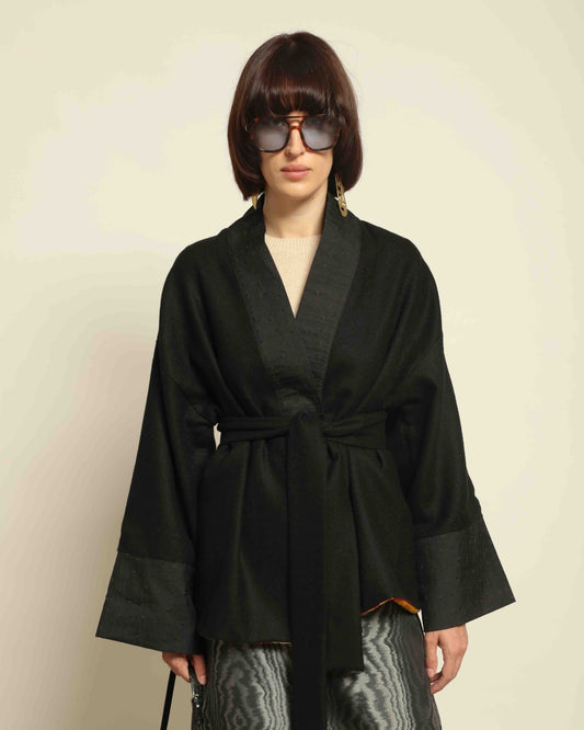 The model is wearing the Obidi Midnight Kantha Jacket in pure black, made of wool with a silk collar and Kantha silk lining, a timeless and versatile piece.